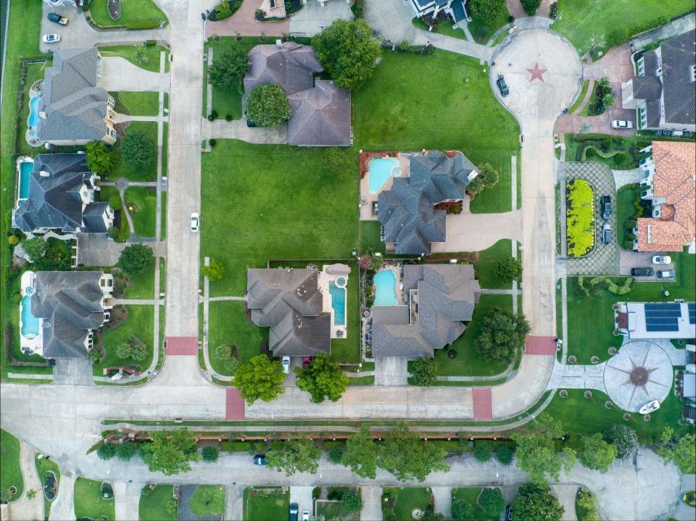 Overhead aerial view of a master-planned Texas subdivision with pools, wide lots and a star set into the cul-de-sac
