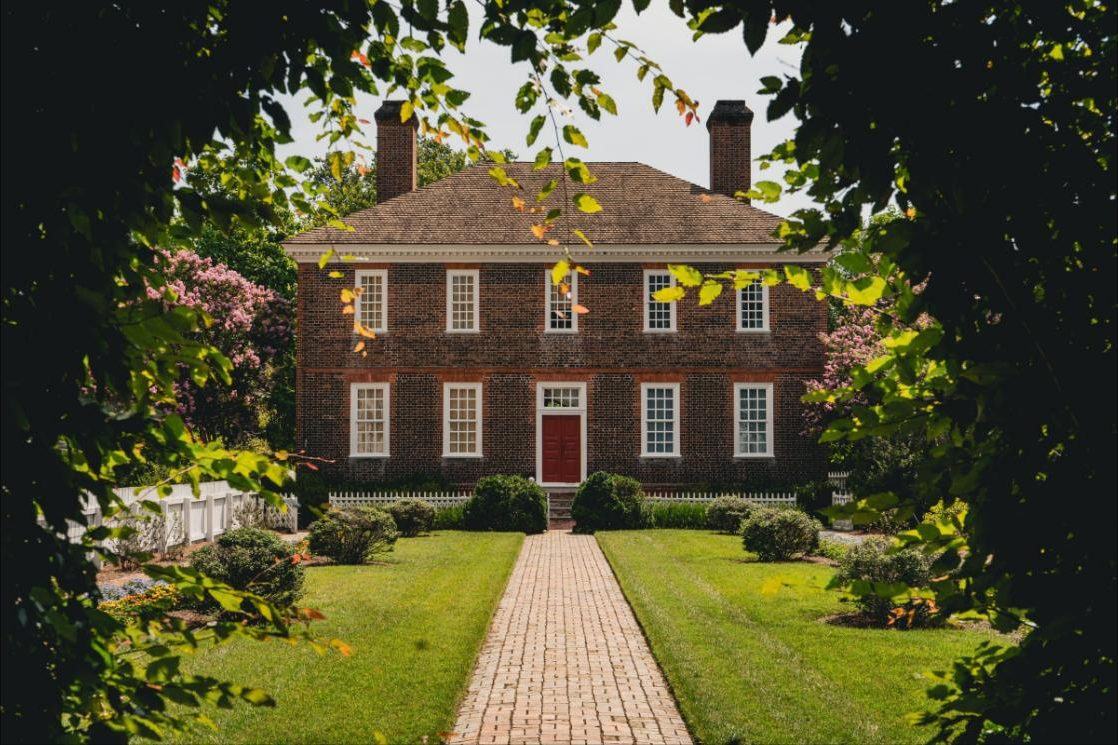 Traditional brick house with symmetrical windows and twin chimneys at the end of a brick walk